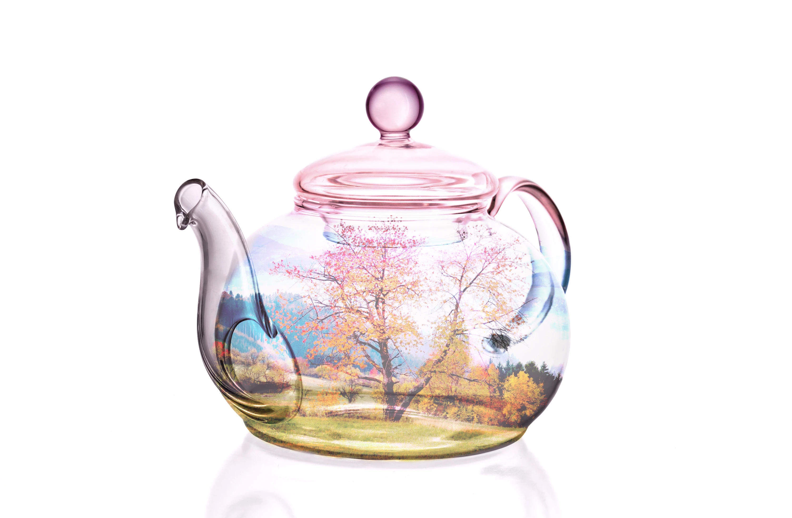 Double exposure of a clear glass teapot overlaid with a spring meadow and blossoming trees.